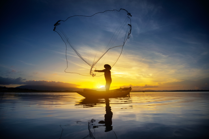 Silhouette of Fisherman Casting Fishing Net into the River